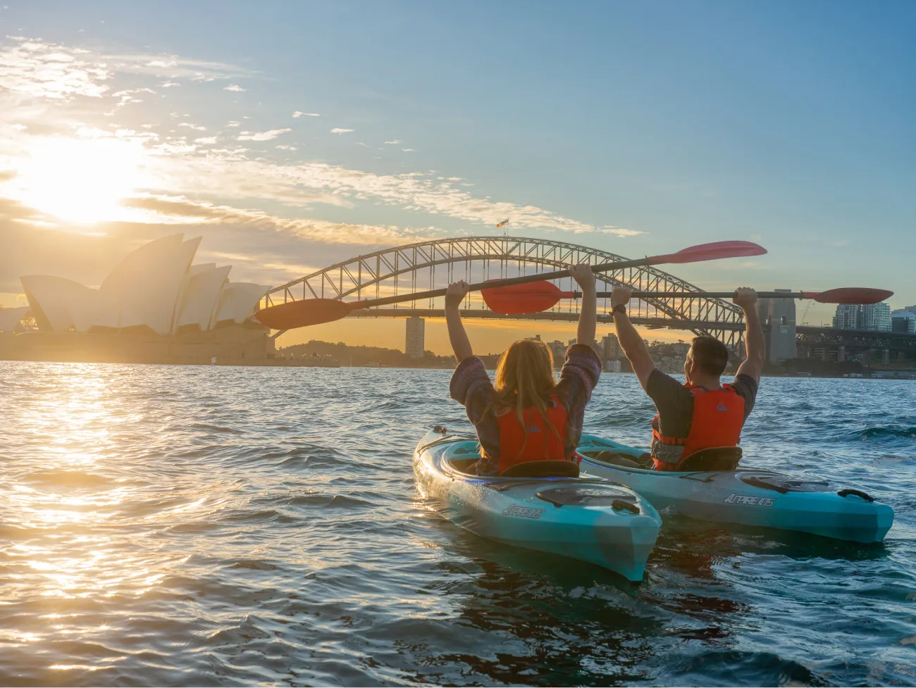 Couple kayaking at sunrise in Sydney with Opera House and Harbour Bridge in view